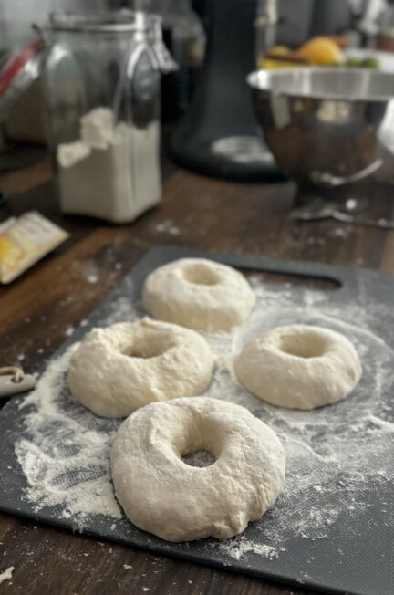 Vier geformte Bagel-Teiglinge auf einem bemehlten Brett, bereit für die Zubereitung im Airfryer