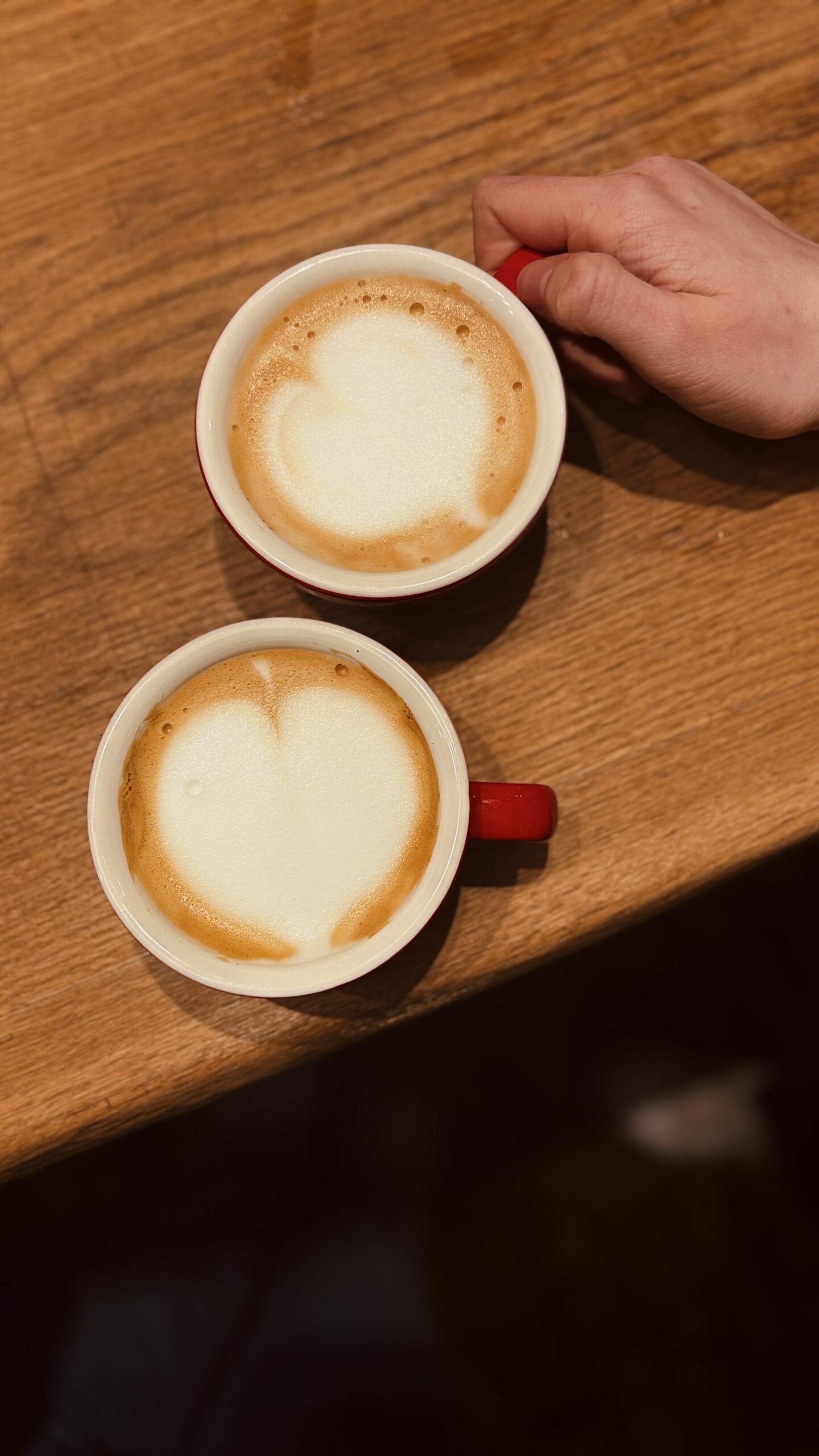 Zwei Cappuccinos mit Herz-Latte-Art auf einem Holztisch – Symbol für achtsamen Kaffeegenuss im Alltag